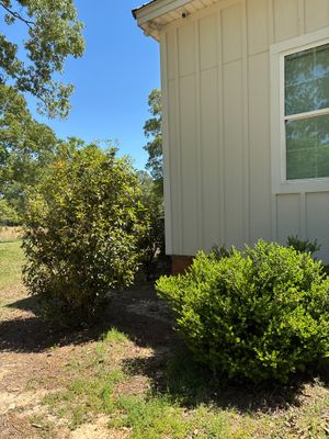 A residential home exterior with landscaping and shrubs, showing no visible foundation repair work, drainage hardware,