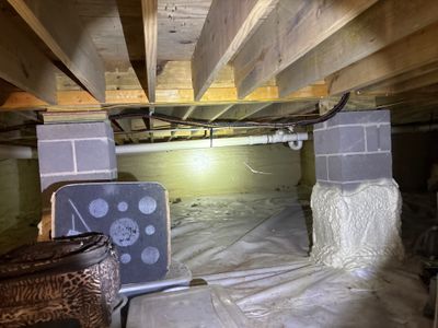 Active crawlspace encapsulation and waterproofing installation with vapor barrier and drainage materials staged under a