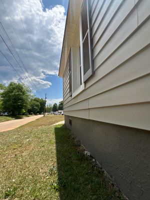 Exterior view of a house foundation and yard showing no visible repair work, installed hardware, or drainage systems—a