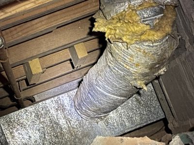 A crawlspace encapsulation system in progress, showing yellow insulation and white vapor barrier material being