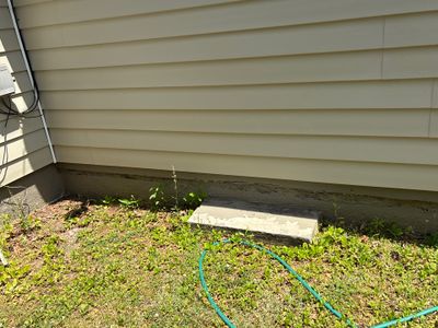 Exterior yard drainage system installation with green drainage pipes and a concrete drainage box visible along the