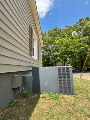 An exterior black plastic catch basin with grated top is installed in the yard near the house foundation for surface