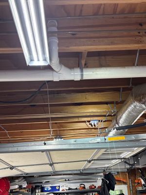 Interior crawlspace with LED lighting and HVAC ductwork installed, showing drainage pipe and wiring in progress during