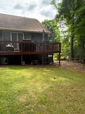 Exterior view of a residential house with a wooden deck and manicured lawn, showing no visible foundation repair work,
