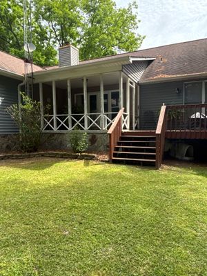 A residential home exterior with a covered porch, deck, and well-maintained lawn, showing no visible foundation repair