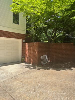 A residential driveway and brick foundation wall with a garage door visible, showing no active repair work or installed