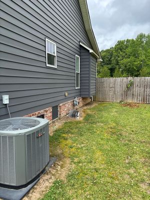 Exterior view of a house with a yard showing an HVAC unit and wooden fence, with no visible foundation repair or