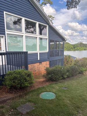 Exterior view of a modern house on a waterfront lot with a deck, manicured lawn, and landscaping, showing no visible