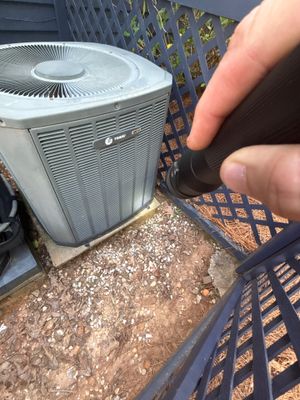 An exterior AC unit is visible with a gravel base and drainage work being performed in the adjacent yard area with a