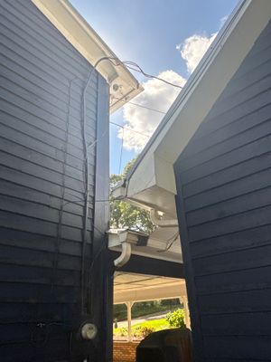 Installation of crawlspace encapsulation materials visible between two dark foundation walls with white plastic