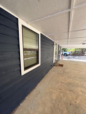 A foundation wall being prepared or treated with dark waterproofing membrane application, with windows installed and