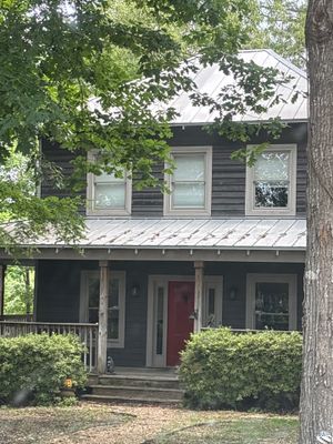 A well-maintained two-story residential home with dark siding, white trim, and landscaping, showing no visible