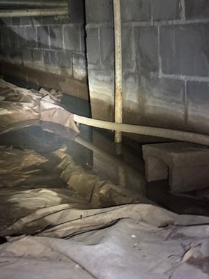 A crawlspace or basement foundation area shows interior drainage channel/pipe installation along the perimeter with