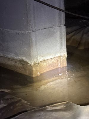 Foundation wall with visible waterproofing membrane and interior drainage system installed along the base, with water