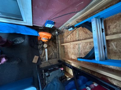An active crawlspace encapsulation and interior drainage installation with blue vapor barrier material, wooden support