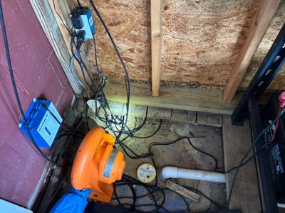 Interior crawlspace or basement with drainage pipe installation in progress, including visible sump pump equipment