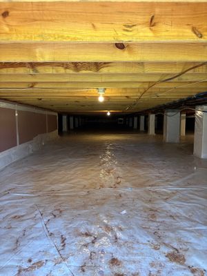 A wet crawl space with standing water and exposed soil showing moisture intrusion and water damage prior to