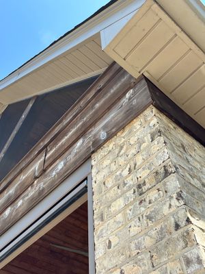 Exterior view of a stone foundation with roof soffit and fascia, showing no visible repair work or installed