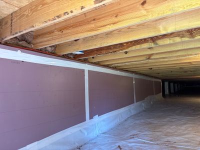 A crawlspace encapsulation project in progress showing white polyethylene membrane being installed on foundation walls