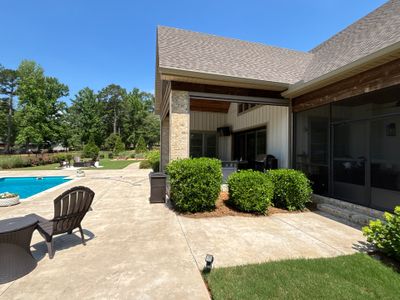 A residential backyard with completed hardscape patio, decorative landscaping, and pool area showing finished exterior