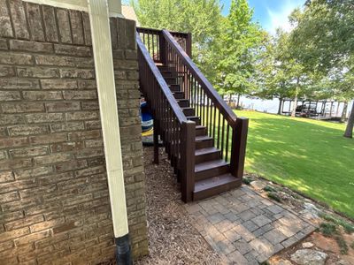 Exterior view of a residential foundation with a deck, stairs, and manicured lawn showing no visible foundation repair