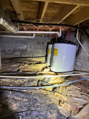 An active crawlspace waterproofing installation showing interior drainage piping along the foundation perimeter and a