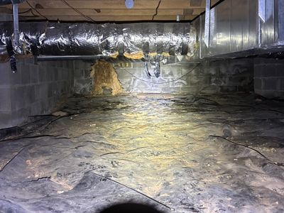 A basement or crawlspace floor with active installation of interior drainage channels and waterproofing membrane