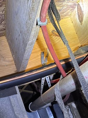 Interior drainage system installation in progress with pipes and straps visible along a foundation or basement