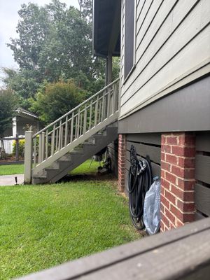 Exterior view of a house with brick foundation, wooden deck with railings, and green lawn showing no visible foundation