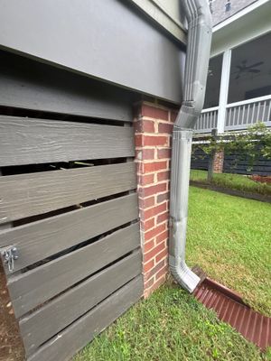 Exterior view of a house with a gray garage door, brick column, and green lawn showing no visible foundation repair or