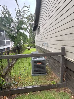 Exterior view of a residential property showing a side yard with an HVAC unit, deck, and landscaping with no visible