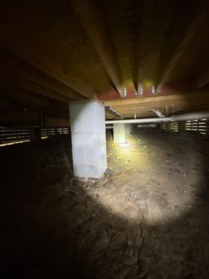 A crawlspace or basement interior showing an interior drainage channel or pipe installation along the foundation,