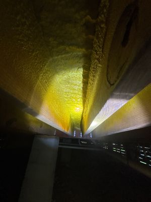 Interior basement or crawl space with yellow lighting illuminating what appears to be drainage infrastructure
