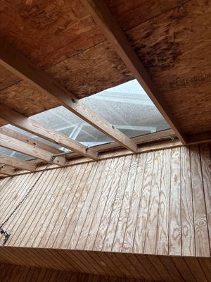 Interior crawl space showing wooden floor joists with skylights above and what appears to be the beginning stages of