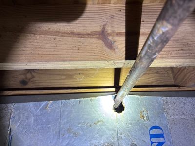 Interior drainage pipe installation along the foundation, with a metal downspout directing water into the system during