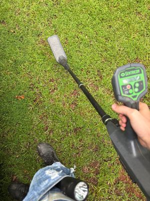 A technician uses a ground-penetrating radar device to survey subsurface conditions in a lawn, likely assessing soil