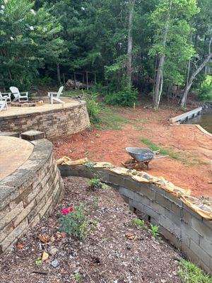 Exterior yard with active foundation and drainage work in progress, showing excavated areas with red clay soil, wooden