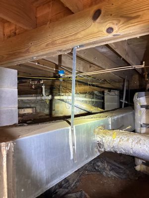 Active installation of interior drainage system with visible perimeter drain channel, support posts, and sump basin pit