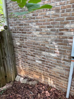 A brick foundation wall with mulch at the base showing no visible repair work or installed hardware, representing the