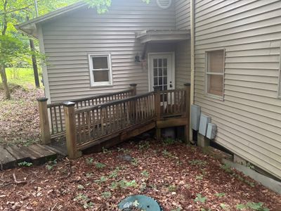 Exterior view of a residential home with a wooden deck and mulched yard showing no visible foundation repair work or