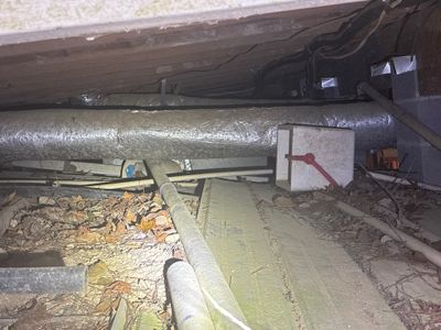 An active crawlspace drainage and encapsulation installation in progress, showing interior perimeter drainage piping
