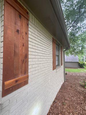 Exterior view of a brick and concrete block house foundation with a red wooden door and window, showing the pre-work