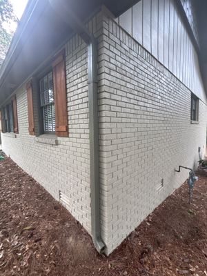 Exterior view of a brick foundation with white painted lower section and no visible repair work, drainage hardware, or