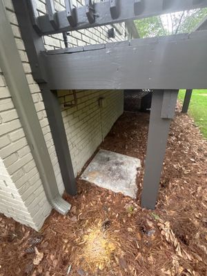 Installation of crawlspace encapsulation system showing grey vapor barrier material being applied to foundation walls