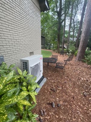 A completed yard drainage installation with an exterior drain box/catch basin visible in the landscaped area alongside
