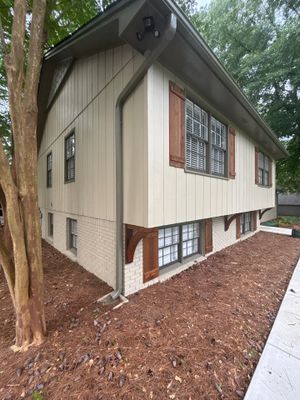 Exterior view of a raised foundation home with mulched yard drainage around the perimeter and a visible downspout