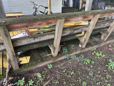 Wooden deck structure with exposed foundation and stored boats/kayaks, showing exterior ground conditions with drainage