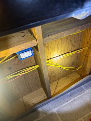 Interior drainage system installation in progress with yellow PVC pipes and electrical outlet box mounted inside a