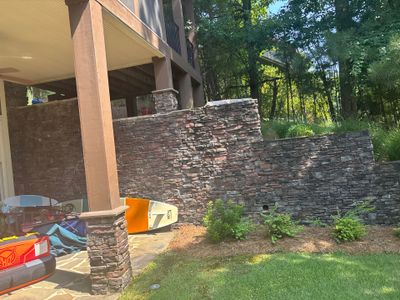 Exterior foundation area with a decorative stone retaining wall under construction and yard drainage infrastructure
