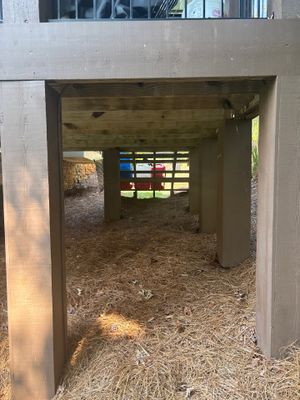 Interior crawl space showing exposed dirt floor with wooden framing and what appears to be vapor barrier or